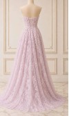Model wearing a strapless lilac floral lace prom dress with a sheer corset bodice and high leg slit