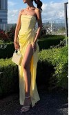 Model wearing a pastel lemon yellow strapless corseted prom gown with a matching neck scarf and high side slit