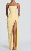 Model wearing a pastel lemon yellow strapless corseted prom gown with a matching neck scarf and high side slit
